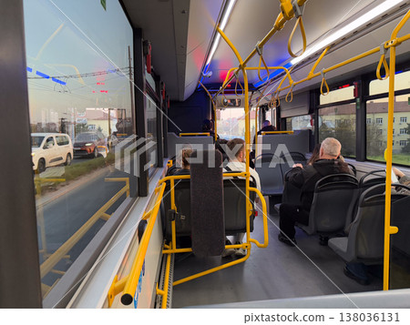 Public bus cabin with passengers and street view through large window during evening ride. Urban commuting, traffic interaction, city transport system, everyday mobility, infrastructure use, routine Public bus cabin with passengers and street view through large window during evening ride. Urban commuting, traffic interaction, city transport system, everyday mobility, infrastructure use, routine 138036131