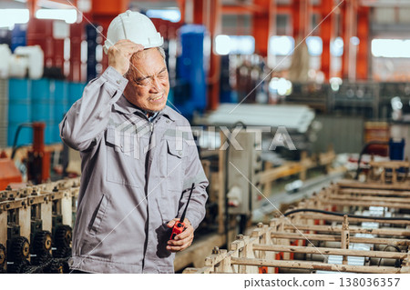 Senior worker headache stressed, feel angry hot uncomfortable hard work in heavy industry factory machine. 138036357