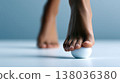 Barefoot african woman balancing foot on small ball performing simple exercise for foot strength and body balance 138036380