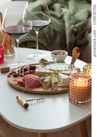 Cozy living room with two glasses of red wine and cheese on table Cozy living room with two glasses of red wine and cheese on table 138036760