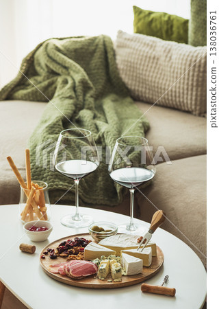 Cozy living room with two glasses of red wine and cheese on table 138036761