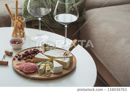 Cozy living room with two glasses of red wine and cheese on table Cozy living room with two glasses of red wine and cheese on table 138036763