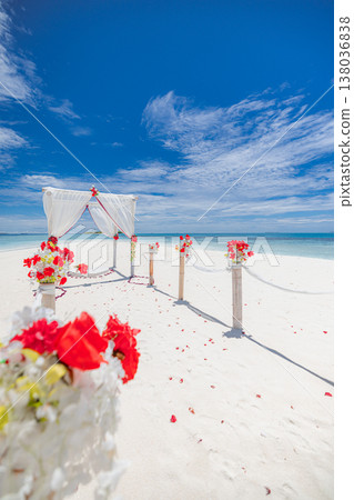 Tropical beach wedding decoration with candles flowers and arch on white sand, blue ocean and sunny sky background, romantic destination ceremony setup 138036838
