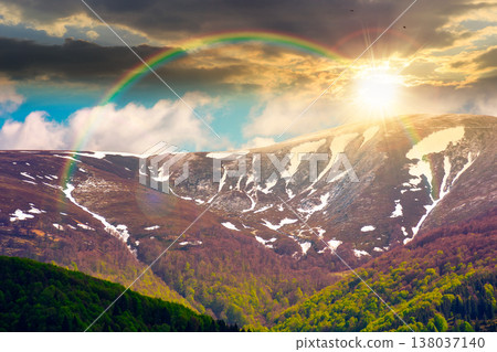 sunset over nature image of ridge with snow capped tops in spring landscape. mountain background wallpaper. greenery scenery with forested slopes under rainbow and sky with clouds sunset over nature image of ridge with snow capped tops in spring landscape. mountain background wallpaper. greenery scenery with forested slopes under rainbow and sky with clouds 138037140