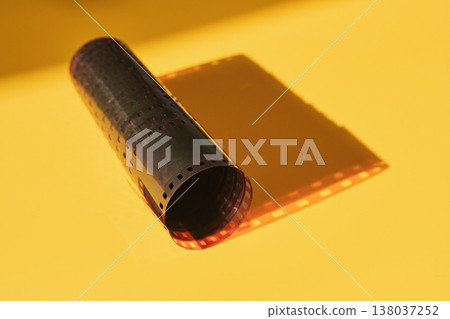 Film strip laying unrolled with shadow reflecting its iconic perforations Film strip laying unrolled with shadow reflecting its iconic perforations 138037252