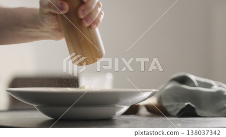 man add dry seasoning of italian herbs over cheese to pasta into plate closeup 138037342
