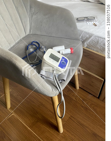 Medical equipment and supplies placed on a chair near a bed in a living space or hospital room 138037516