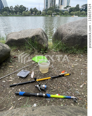 Fishing gear is set up near a lake with buildings in the background during a cloudy day Fishing gear is set up near a lake with buildings in the background during a cloudy day 138037524
