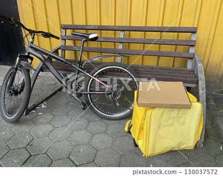 yellow backpack near the bike on the sidewalk. delivery concept 138037572