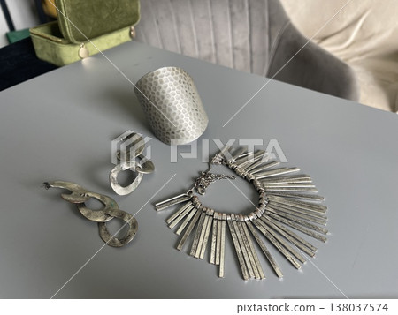 Various silver jewelry pieces displayed on a gray surface in a home setting during daylight hours Various silver jewelry pieces displayed on a gray surface in a home setting during daylight hours 138037574