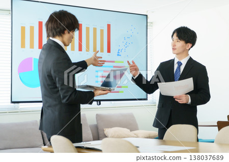 一位年輕人在辦公室裡做演示,講解螢幕上顯示的圖表。 一位年輕人在辦公室裡做演示,講解螢幕上顯示的圖表。 138037689