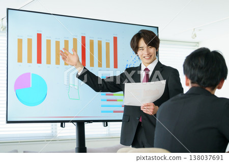 一位年輕人在辦公室裡做演示,講解螢幕上顯示的圖表。 一位年輕人在辦公室裡做演示,講解螢幕上顯示的圖表。 138037691