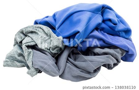A messy heap of blue and gray clothing is placed on a clear surface. The wrinkled fabric suggests it has just come out of a laundry cycle, ready to be sorted or folded 138038110