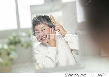 一位老婦人對著鏡子梳頭。 138038238