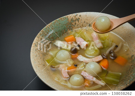 A beautiful consommé soup featuring sweet, small pearl onions and colorful carrots. 138038262