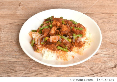 spicy stir fried slice yard long bean with crispy pork and lemon grass in curry sauce on rice in plate spicy stir fried slice yard long bean with crispy pork and lemon grass in curry sauce on rice in plate 138038585
