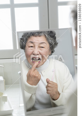 老婦人照鏡子時擔心自己的牙齦 老婦人照鏡子時擔心自己的牙齦 138038609
