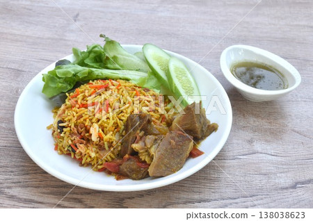 biryani rice cooked with braised beef meat stew in curry and fresh vegetable salad on plate dipping spicy chili sauce biryani rice cooked with braised beef meat stew in curry and fresh vegetable salad on plate dipping spicy chili sauce 138038623