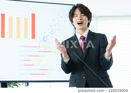 A young man passionately explains a graph displayed on a screen in an office. A young man passionately explains a graph displayed on a screen in an office. 138039008
