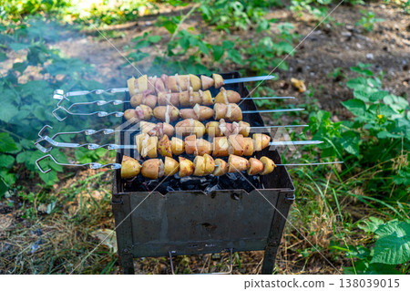 Potatoes with lard are grilled on a skewer over open flames, creating a rustic and flavorful outdoor meal. Potatoes with lard are grilled on a skewer over open flames, creating a rustic and flavorful outdoor meal. 138039015