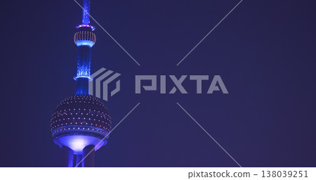 Oriental Pearl Tower illuminated in vibrant blue light against dark twilight sky, captured during evening with glowing observation sphere and antenna spire 138039251