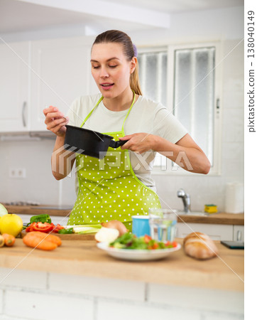 Woman in apron cooking delicious soup in pot in kitchen Woman in apron cooking delicious soup in pot in kitchen 138040149