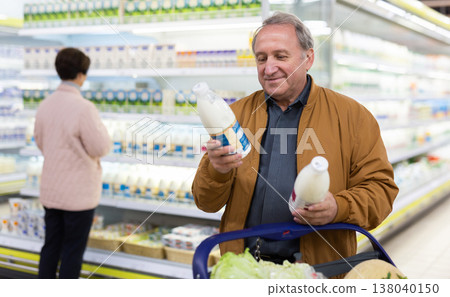 Mature couple choosing jug of milk in dairy department in grocery store Mature couple choosing jug of milk in dairy department in grocery store 138040150