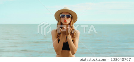 Summer vacation, beautiful young woman blowing kiss in swimsuit, sunglasses, on the beach on sea Summer vacation, beautiful young woman blowing kiss in swimsuit, sunglasses, on the beach on sea 138040767