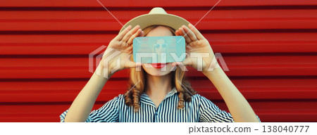 Close up portrait of woman taking selfie with mobile phone stretching her hands on red background 138040777
