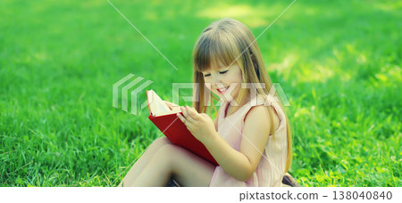 Happy little girl child reading book sitting in summer park 138040840