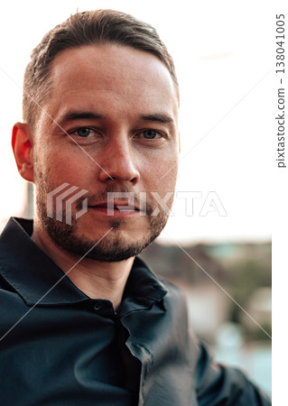 Man sits in outdoor setting with soft lighting during sunset in a casual moment Man sits in outdoor setting with soft lighting during sunset in a casual moment 138041005