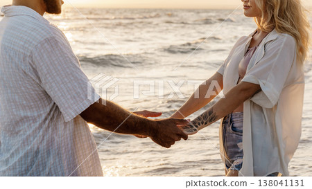 Couple holding hands at sunset by the ocean shoreline 138041131