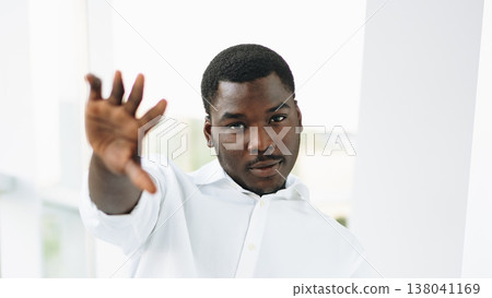 Man gesturing with hand in bright indoor space during a casual moment 138041169