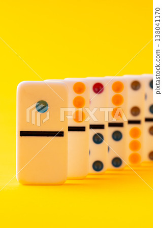 Bright yellow background shows classic dominoes arranged in a row with different designs Bright yellow background shows classic dominoes arranged in a row with different designs 138041170