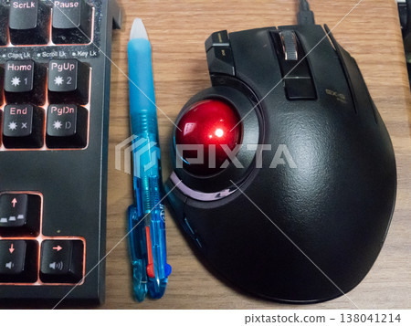 Next to my well-used keyboard are a multi-color ballpoint pen and a high-performance trackball. Next to my well-used keyboard are a multi-color ballpoint pen and a high-performance trackball. 138041214