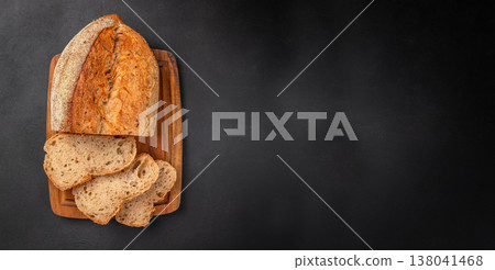 Seeded Bread Loaf with Slices on Wooden Board over Black Background Seeded Bread Loaf with Slices on Wooden Board over Black Background 138041468