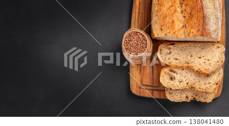 Seeded Bread Loaf with Slices on Wooden Board over Black Background 138041480