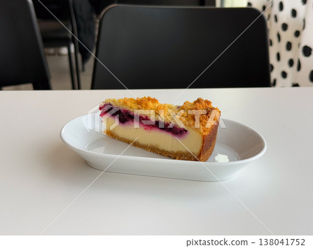 Slice of blueberry cheesecake with crumble topping served on white plate in minimal setting. Dessert portion styling, cafe pastry display, creamy texture, berry filling, bakery menu concept Slice of blueberry cheesecake with crumble topping served on white plate in minimal setting. Dessert portion styling, cafe pastry display, creamy texture, berry filling, bakery menu concept 138041752