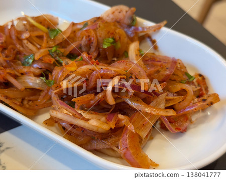 Marinated onion salad with herbs and spices served as appetizer in restaurant setting. Balkan side dish, pickled preparation, flavor enhancement, culinary tradition, table serving concept Marinated onion salad with herbs and spices served as appetizer in restaurant setting. Balkan side dish, pickled preparation, flavor enhancement, culinary tradition, table serving concept 138041777