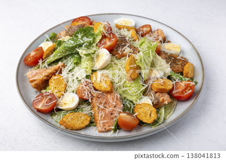 Caesar salad with trout (salmon), cherry tomatoes, croutons, parmesan cheese, quail eggs and romaine lettuce. Traditional American dish. Close-up, selective focus. 138041813