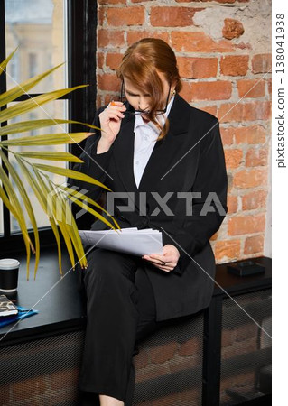 Hiring specialist examines CVs with focus near window and plants Hiring specialist examines CVs with focus near window and plants 138041938