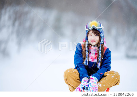 A young woman in ski wear sitting on the snow. A young woman in ski wear sitting on the snow. 138042266