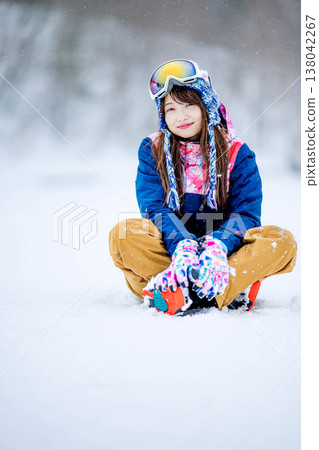 A young woman in ski wear sitting on the snow. A young woman in ski wear sitting on the snow. 138042267