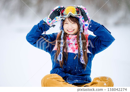 A young woman in ski wear sitting on the snow. A young woman in ski wear sitting on the snow. 138042274