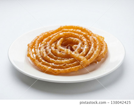 Traditional indian jalebi sweet spiral fried pastry on white plate, close-up studio shot, indian food Traditional indian jalebi sweet spiral fried pastry on white plate, close-up studio shot, indian food 138042425