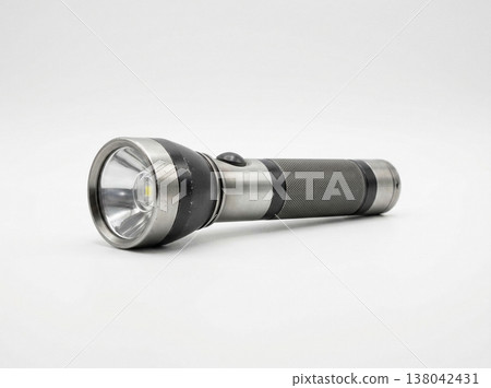 Durable led metal flashlight with textured grip and bright light beam against a clean white background, studio shot 138042431