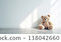 Soft Teddy Bear Sitting Alone on Wooden Floor in Bright Minimal Nursery With Sunlit Wall 138042660