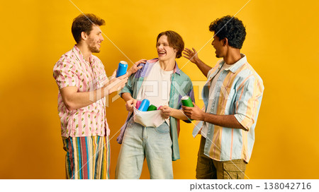 Group of young friends holding colorful cans and laughing together on yellow background. Group of young friends holding colorful cans and laughing together on yellow background. 138042716
