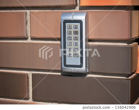 Electronic keypad on brick wall. Digital security device for access control system. Numeric button for password entry and home safety. Modern technology for building entry protection. Electronic keypad on brick wall. Digital security device for access control system. Numeric button for password entry and home safety. Modern technology for building entry protection. 138042906