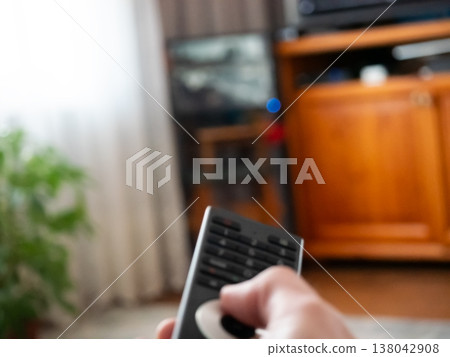 Person holding remote control pointing at television screen. Watching media entertainment at home. Leisure activity in living room, relaxation concept. Broadcasting channel changing device. Person holding remote control pointing at television screen. Watching media entertainment at home. Leisure activity in living room, relaxation concept. Broadcasting channel changing device. 138042908